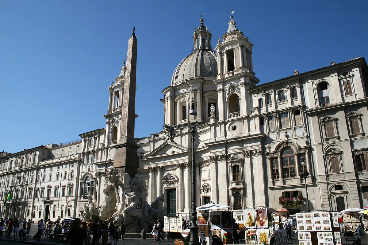 Bernini's Fountain of the Four Rivers in Piazza Navona, with its obelisk, in front of the dome and bell towers of Sant'Agnese in Agone.